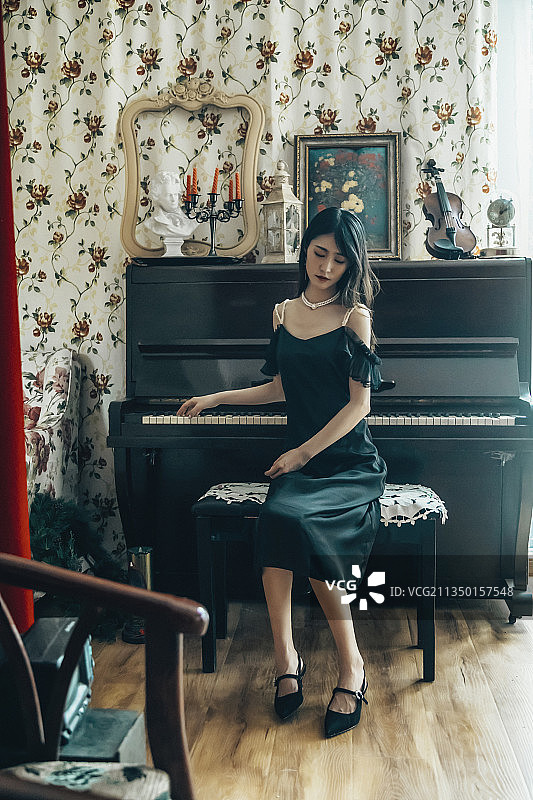 室内穿着黑色连衣裙弹钢琴的女孩图片素材
