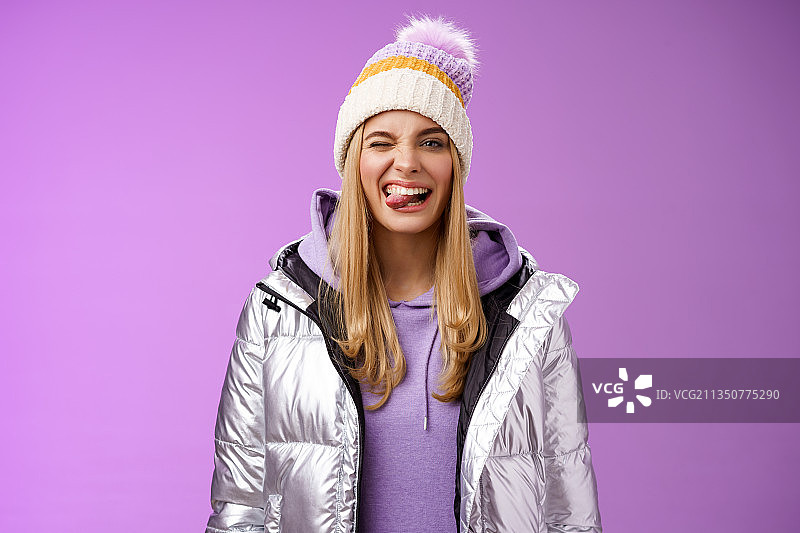 穿着暖和衣服的年轻女子的肖像，站在紫色的背景下图片素材