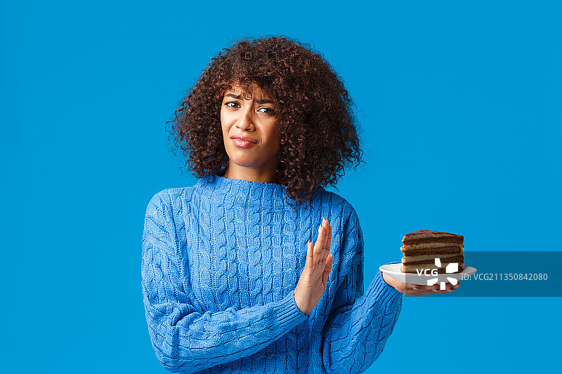 年轻女子的肖像在蓝色的背景下拿着蛋糕图片素材