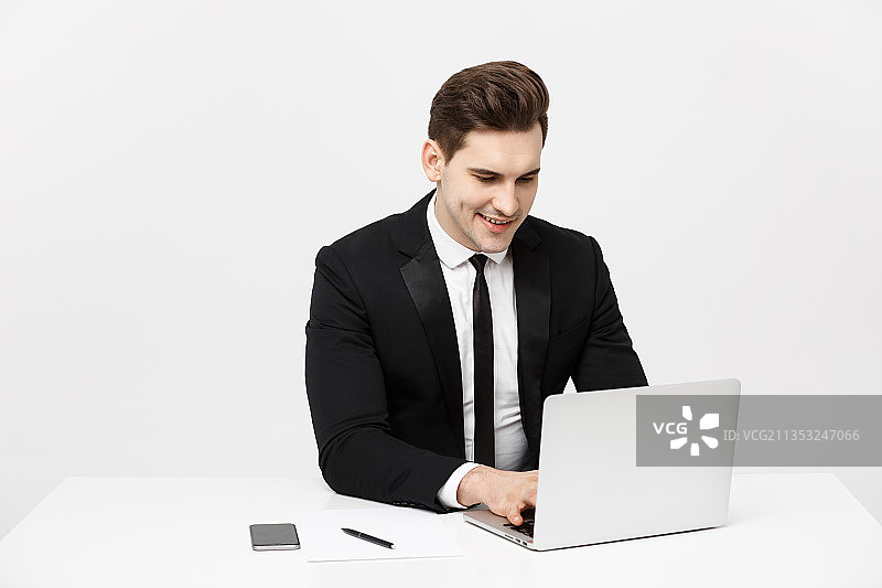 微笑的商人坐在白色背景下使用笔记本电脑图片素材
