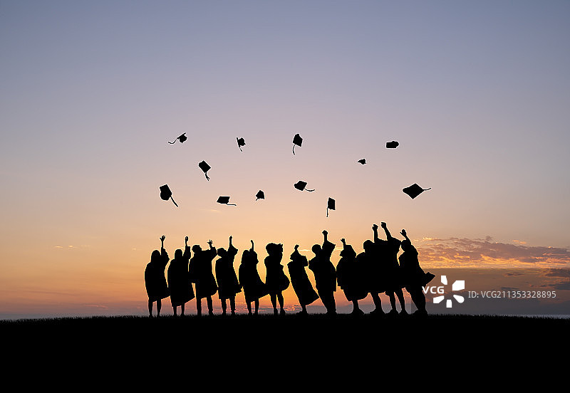 一群大学毕业生在毕业典礼后穿着学士服向天空扔学士帽图片素材