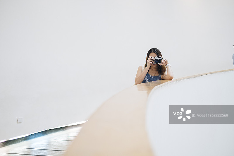 年轻的亚洲泰国妇女在楼梯上与电影相机拍照蓝色连衣裙。图片素材
