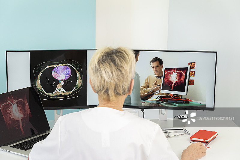 两名医生进行远程会诊，其中一个屏幕上有胃部的医学图像。图片素材