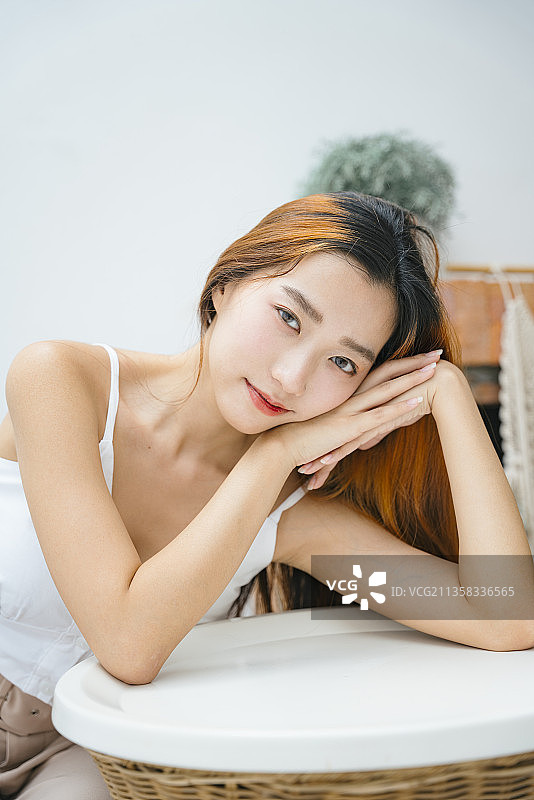 年轻漂亮的女人坐在白色的桌子上。图片素材