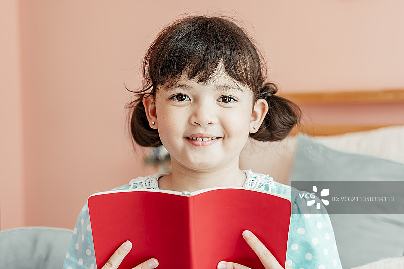 一个女孩在卧室里读红书的特写。图片素材