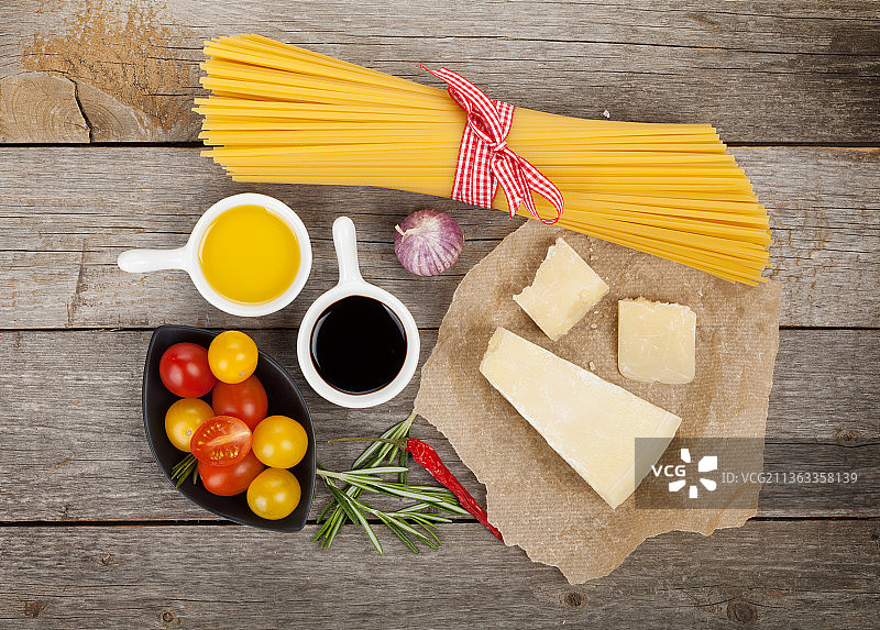 帕尔马干酪，意大利面，番茄，香草和香料，直接上面的未煮熟的意大利面和配料在桌子上图片素材