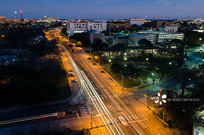 蓝色时段，夜晚城市建筑中灯火通明的街道高视角视野图片素材