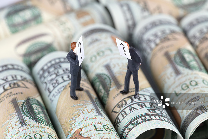 微缩世界两位满脸疑惑的商人模型站在美元钞票上分析图片素材