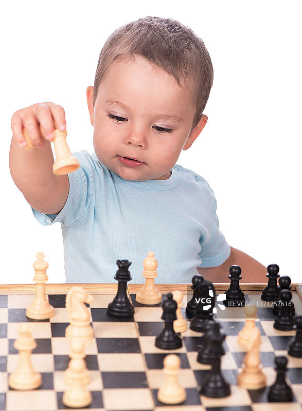小男孩盯着孤立在白色背景下的棋子图片素材