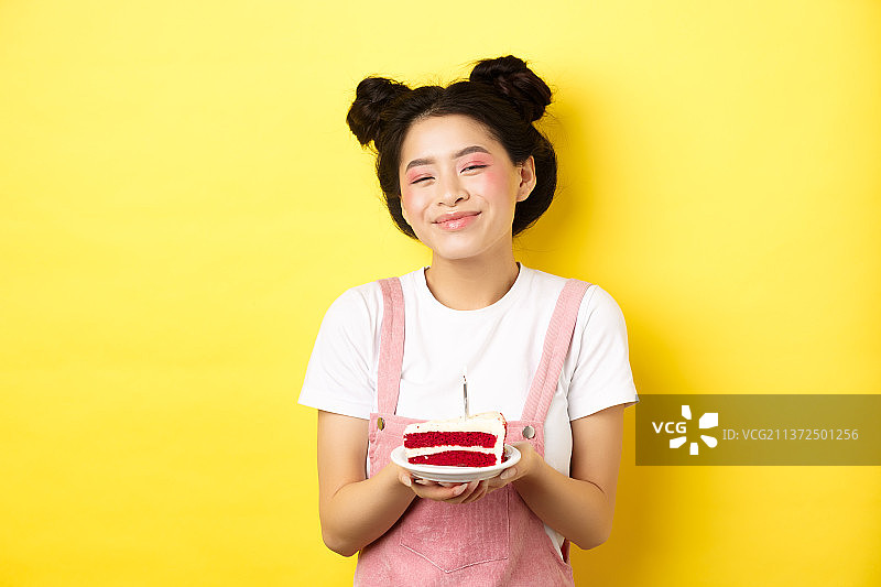 亚洲女孩生日快乐，妆容亮丽，吹蛋糕上的蜡烛图片素材