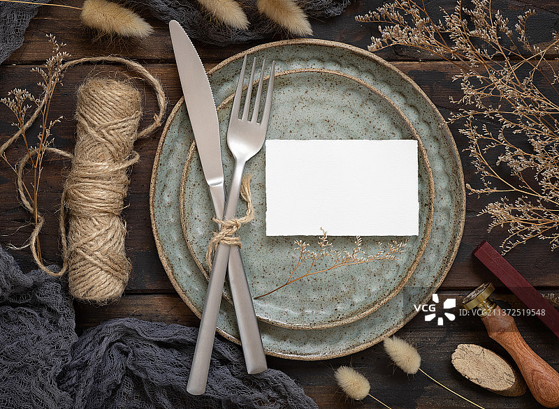 空白纸卡片在盘子上与刀叉和干燥的植物图片素材