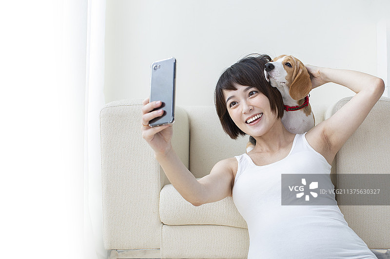 孕妇拿着手机和宠物狗一起拍照图片素材