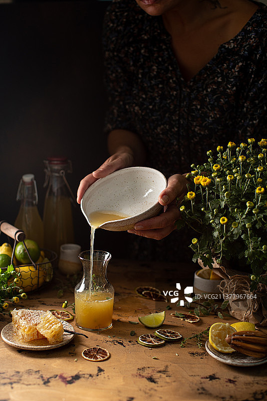 自制柠檬酒，在玻璃器皿中加入蜂蜜、柠檬和酸橙图片素材