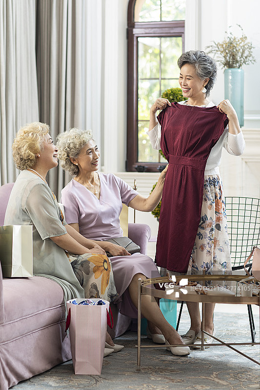 老年女子向朋友展示新买的裙子图片素材