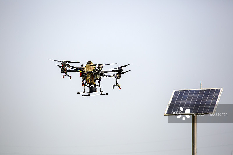 一架农用无人机天空飞行太阳能光伏发电板图片素材