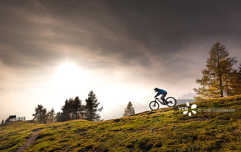 低角度的人骑自行车在山上对天空，多杰，斯洛文尼亚图片素材