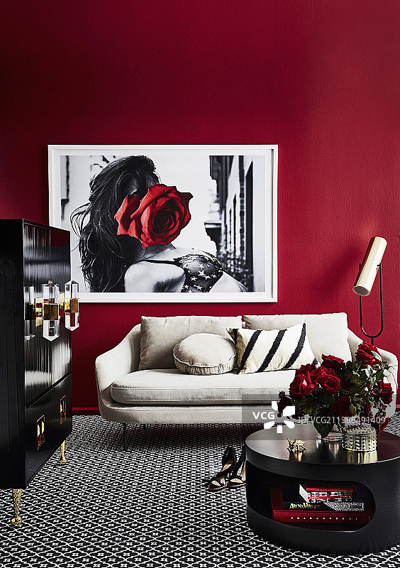 红墙的客厅里有黑色的咖啡桌、黑色的橱柜和明亮的沙发图片素材