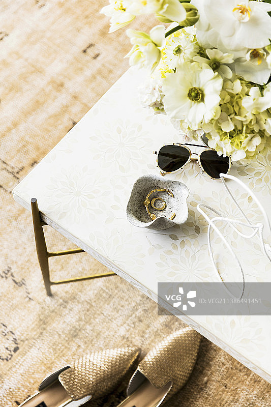咖啡桌上放着一碗珠宝、太阳镜和一束白花图片素材
