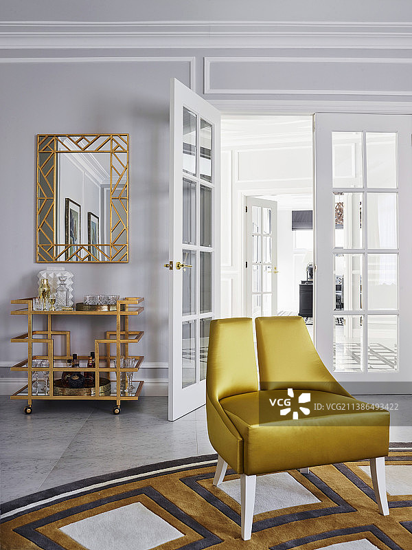 金色的地毯上的设计师椅子，镜子和吧台推车在背景中匹配的颜色图片素材