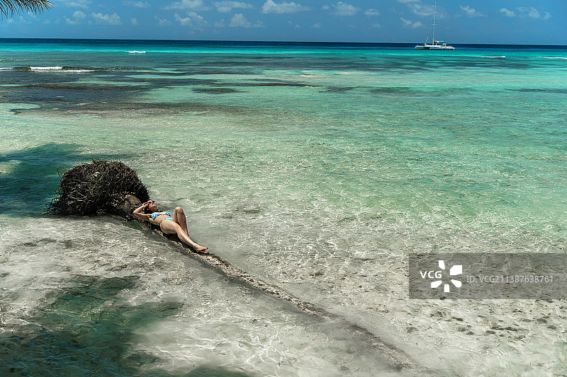 多米尼加共和国，一名女子漂浮在海滩上的棕榈树上图片素材