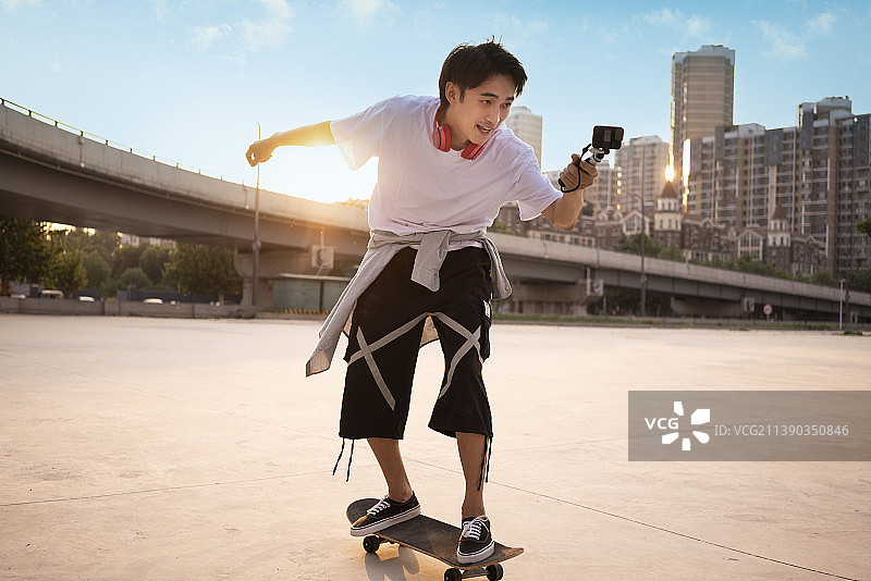 年轻男子滑滑板并用Gopro拍摄图片素材