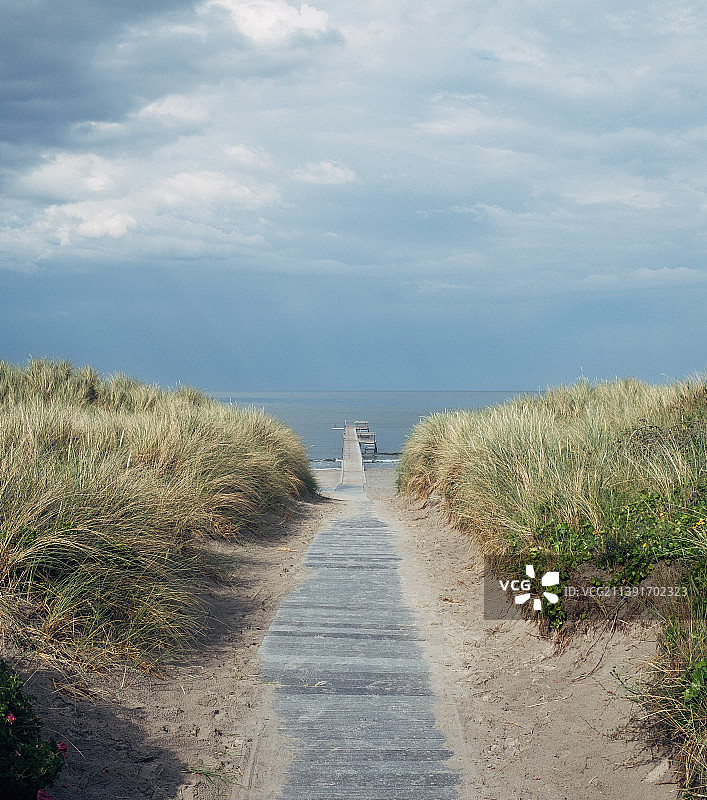 空旷的道路沿着海滩对着天空，布拉滕海滨，丹麦图片素材
