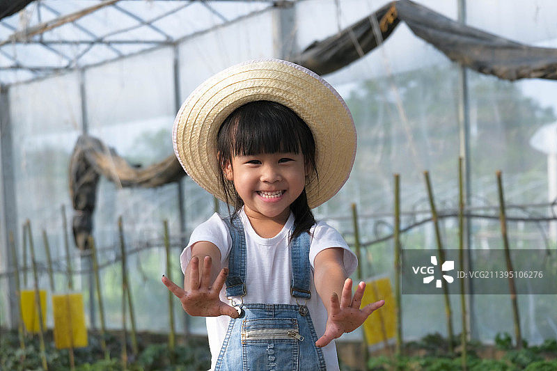 小女孩戴着帽子在花园里帮助她的妈妈，一个小园丁，泰国图片素材