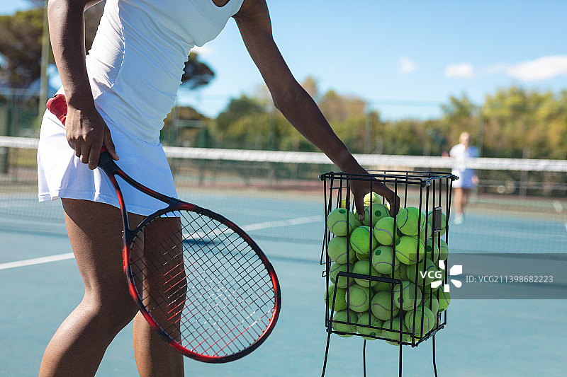 在阳光明媚的日子里，在球场上练习网球的非洲裔美国女运动员的腹部图片素材