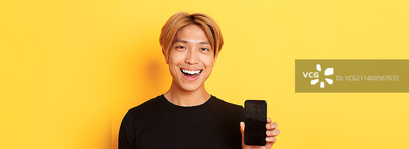 特写的时髦英俊的韩国人显示智能手机屏幕和图片素材