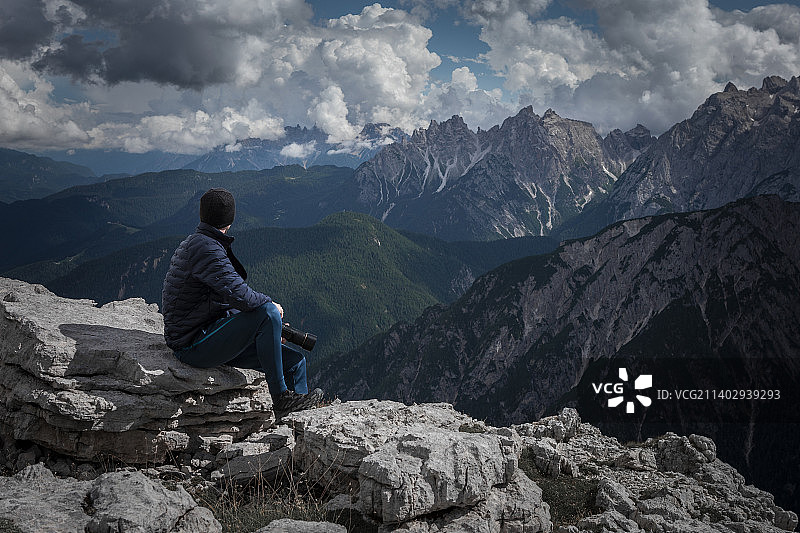 在意大利德雷津宁，一名男子在南蒂罗尔的白云石阿尔卑斯山脉的山峰上拍照，天空中有云图片素材