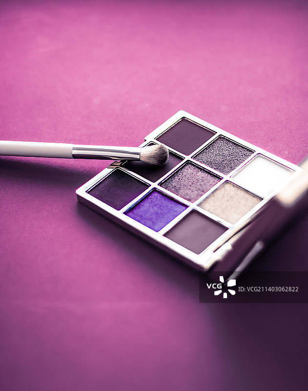 眼影调色板和化妆刷在紫色的背景，眼影图片素材