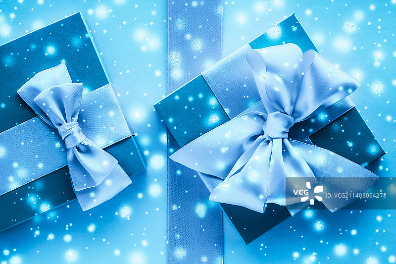 冬天的节日礼物和发光的雪在冻结的蓝色背景图片素材