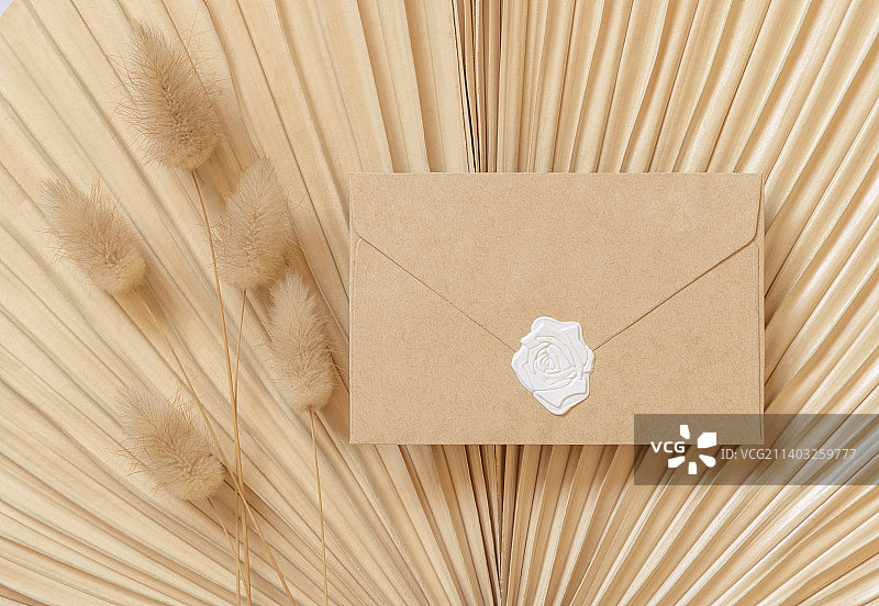 空白密封信封上干米色棕榈叶近兔尾草顶视图，波西米亚婚礼模型图片素材