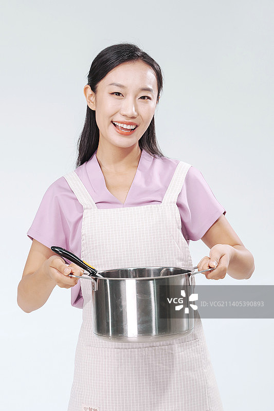做饭的年轻女人拿着汤锅图片素材