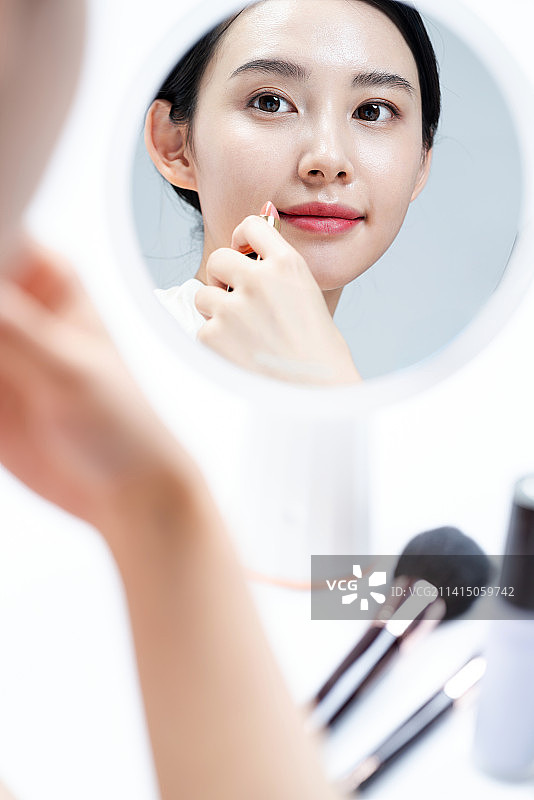年轻漂亮的亚洲女孩在补妆图片素材