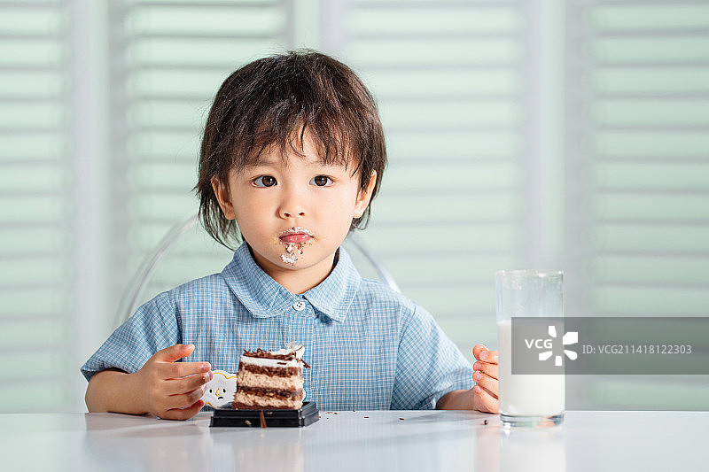 可爱的小男孩吃蛋糕喝牛奶图片素材