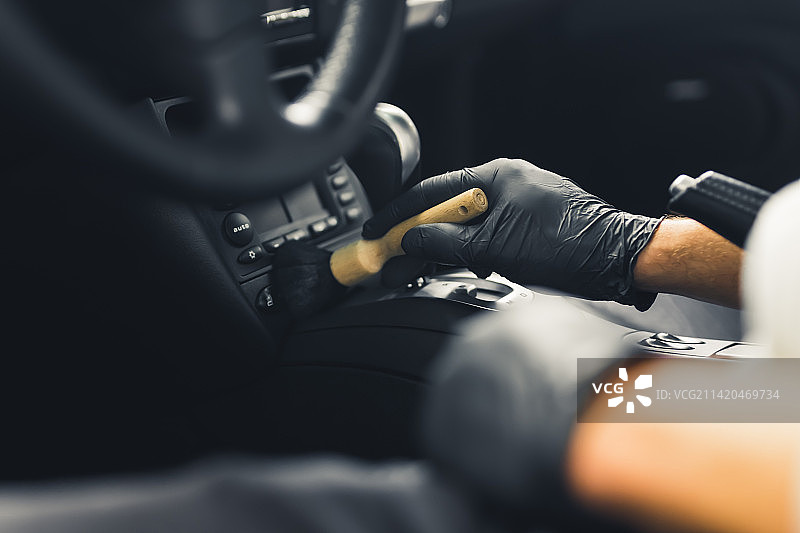 特写镜头，男性双手戴着黑色手套在车内擦拭刷子图片素材