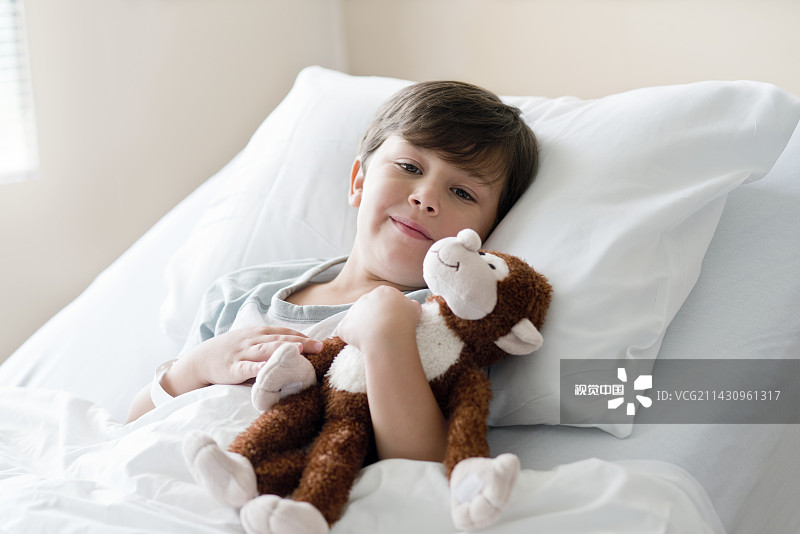 小男孩抱着泰迪熊躺在病床上图片素材