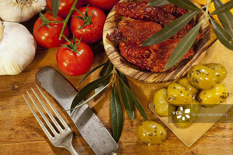新鲜番茄，大蒜，干番茄和橄榄放在木板上图片素材