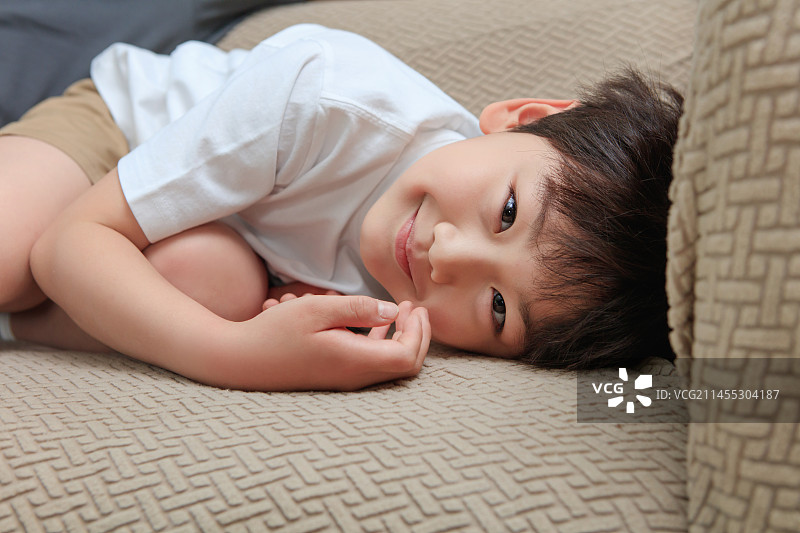 幸福的小男孩躺在沙发上图片素材