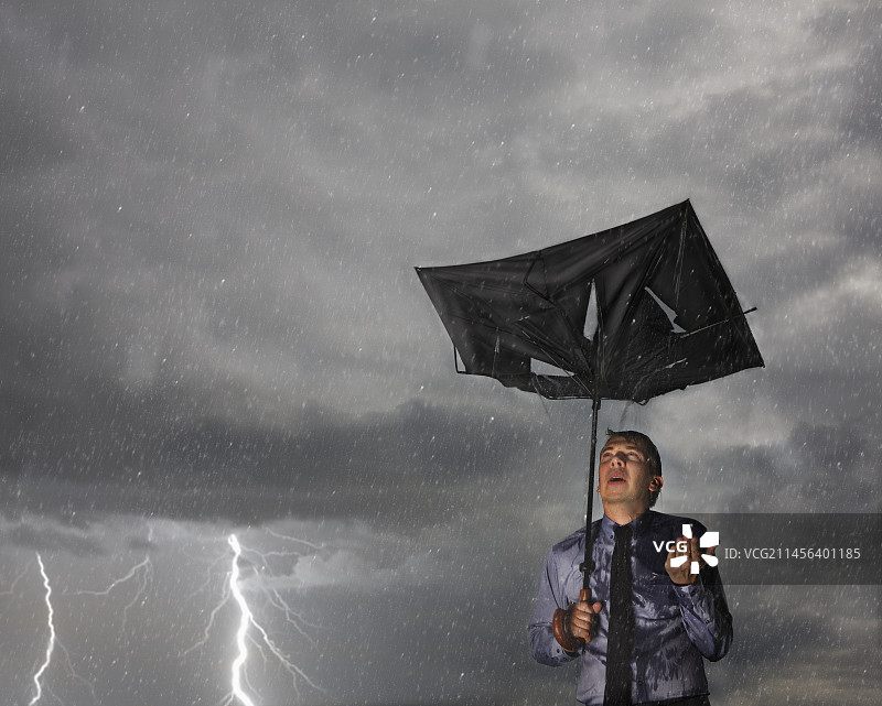 在暴风雨中拿着破伞的商人图片素材