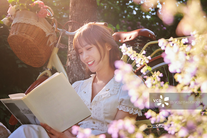 坐在花丛中看书的青年美女图片素材