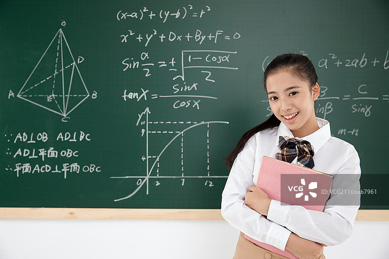 一个中学女生拿着书站在黑板前图片素材