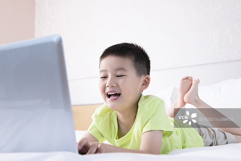 Boy using laptop in bed图片素材