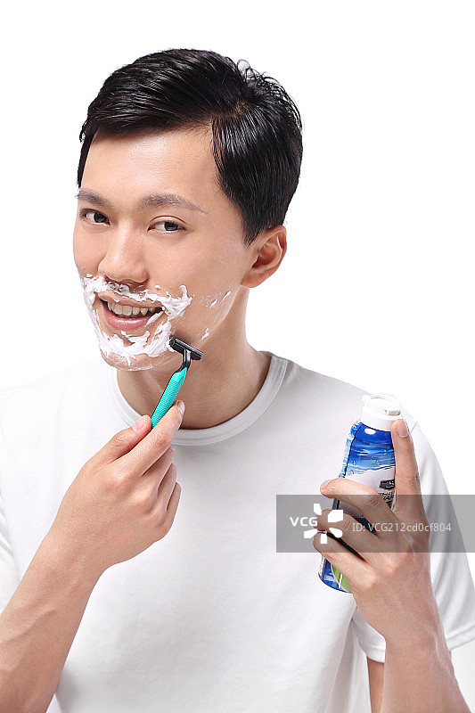 白色背景下面容清爽手拿剃须刀的亚洲男青年图片素材