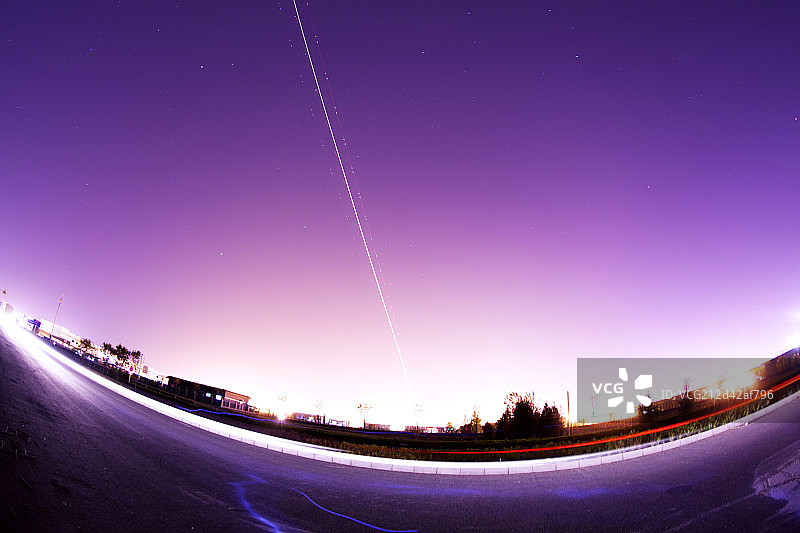 一架正在起飞中的飞机的灯光在夜空中形成了美丽的弧线图片素材