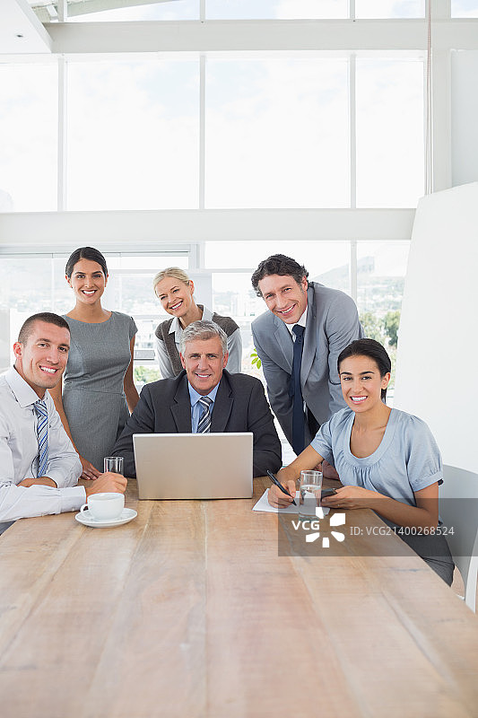 微笑的商务团队在办公室用笔记本电脑一起工作图片素材