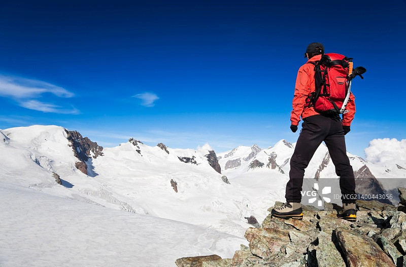 在一次高海拔徒步旅行中，男性徒步者站在蒙特罗莎冰川前。瑞士、欧洲。图片素材