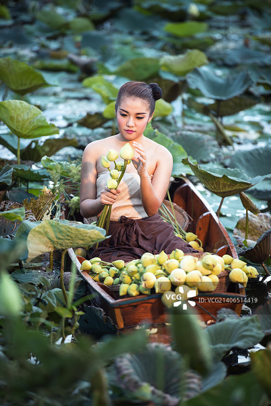 亚洲妇女在泰国农村传统服装坐在船在莲花花园上午图片素材
