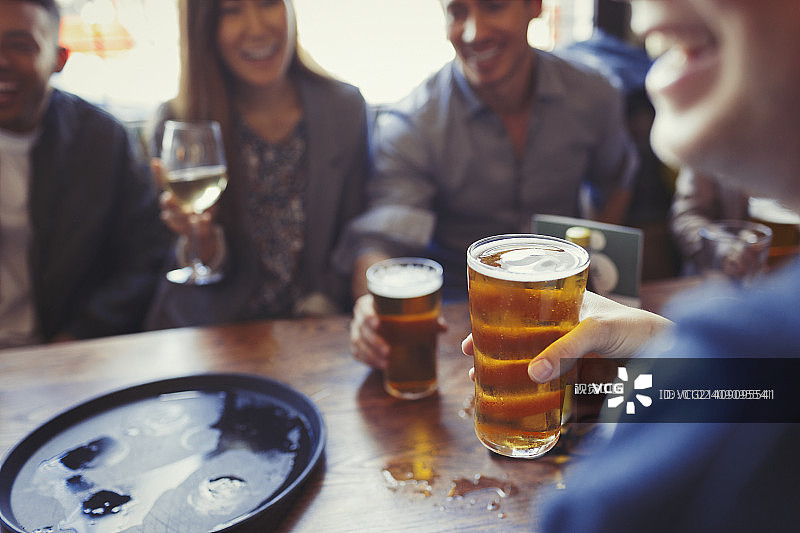 朋友们在酒吧的餐桌上喝着啤酒和葡萄酒图片素材